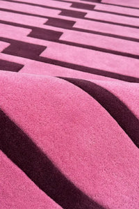 Close-up of a pink and purple textured wool rug with geometric patterns.