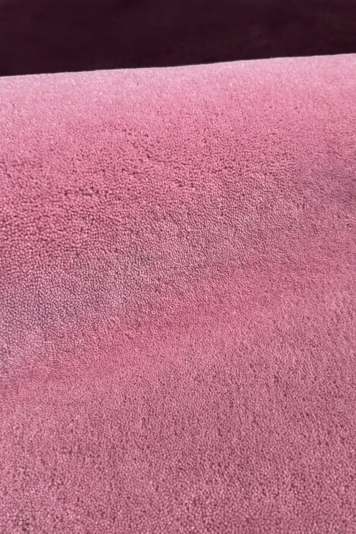 Soft pink and plum block rug surface close-up, purple and pink nursery rug or boho area rug with cozy feel berry