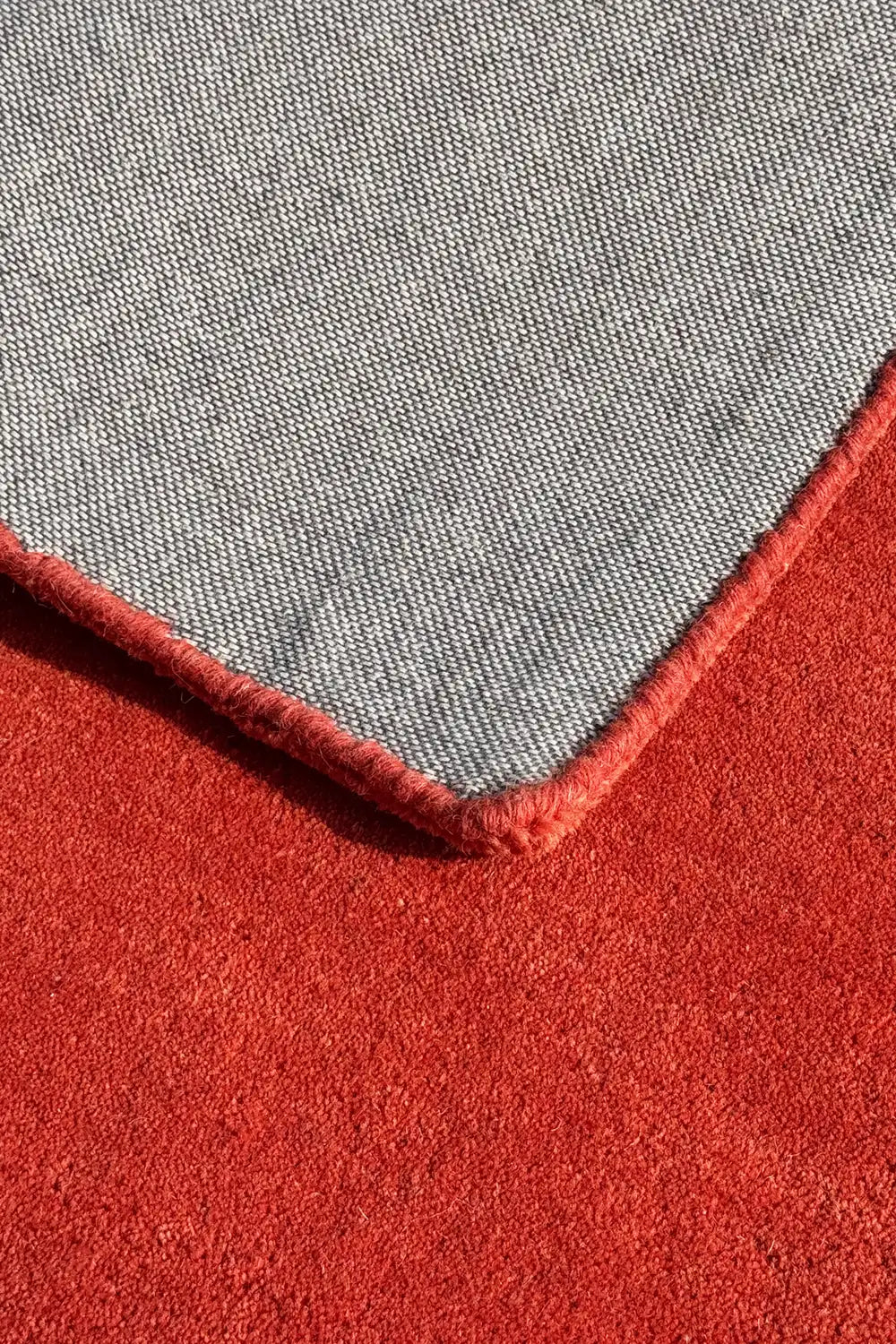 corner detail of an orange wool rug hand tufted from wool