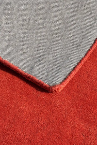 corner detail of an orange wool rug hand tufted from wool