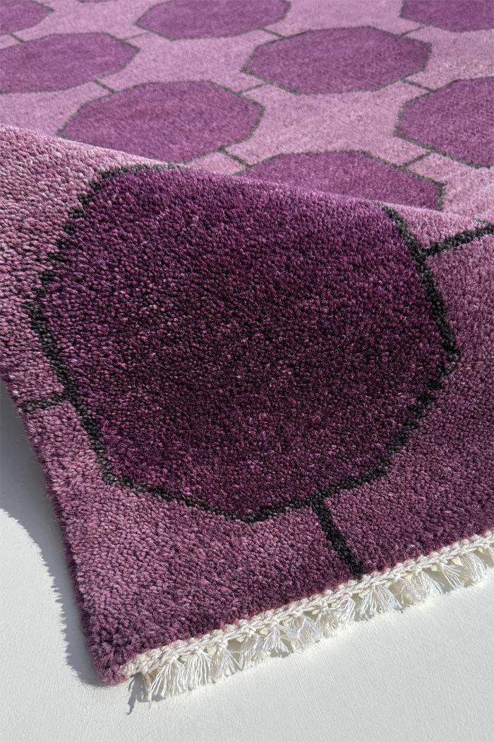 Close-up of a purple hand-knotted rug  texture with geometric pattern on a white background