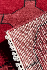 Close-up of a red and black patterned rug with white fringe