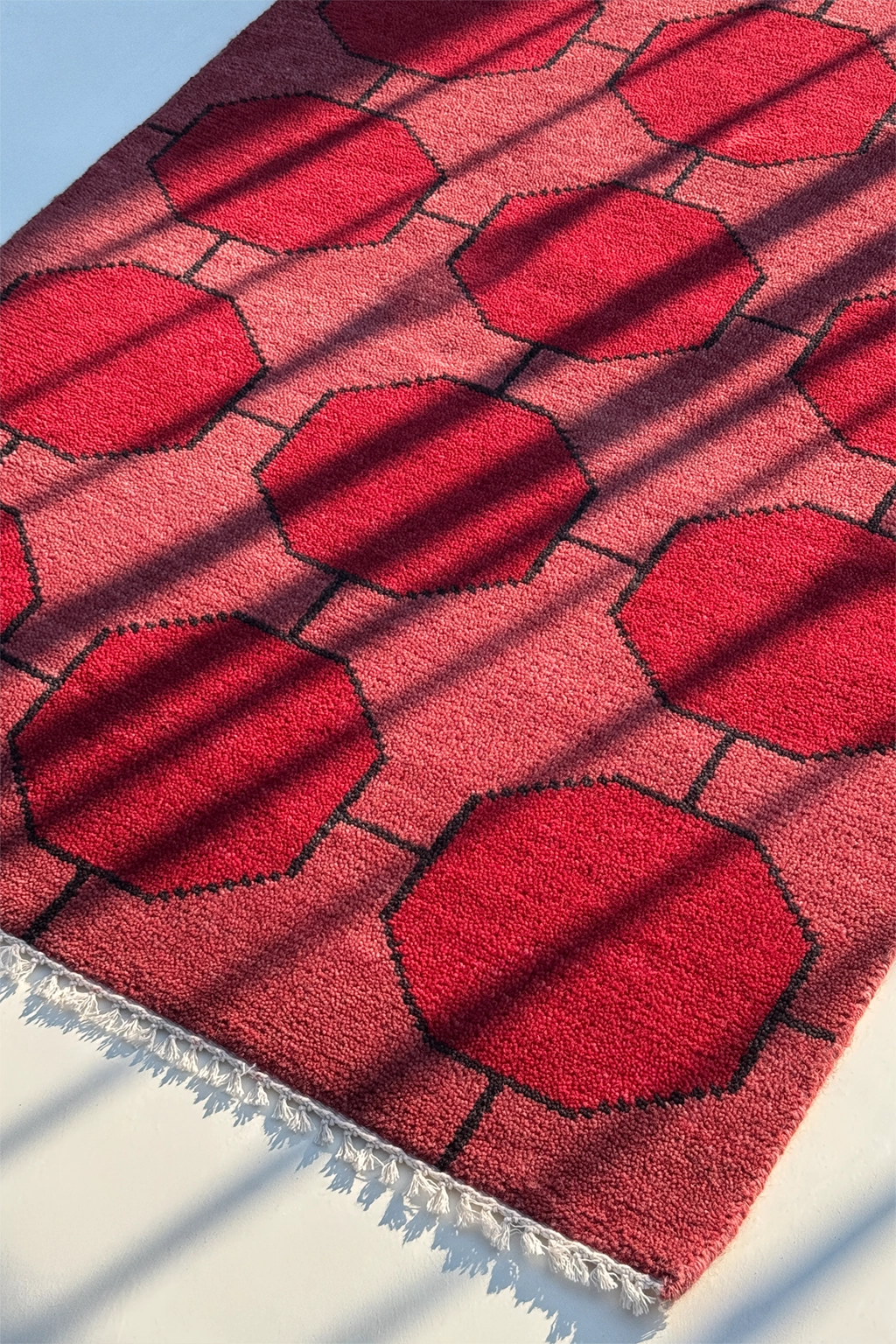 Red textured rug with geometric pattern on a white background