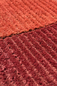 Red and orange wool rug with ridged tufted texture, cozy modern accent for bedroom or office