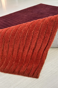 Red and burnt orange textured rug on a light-colored floor