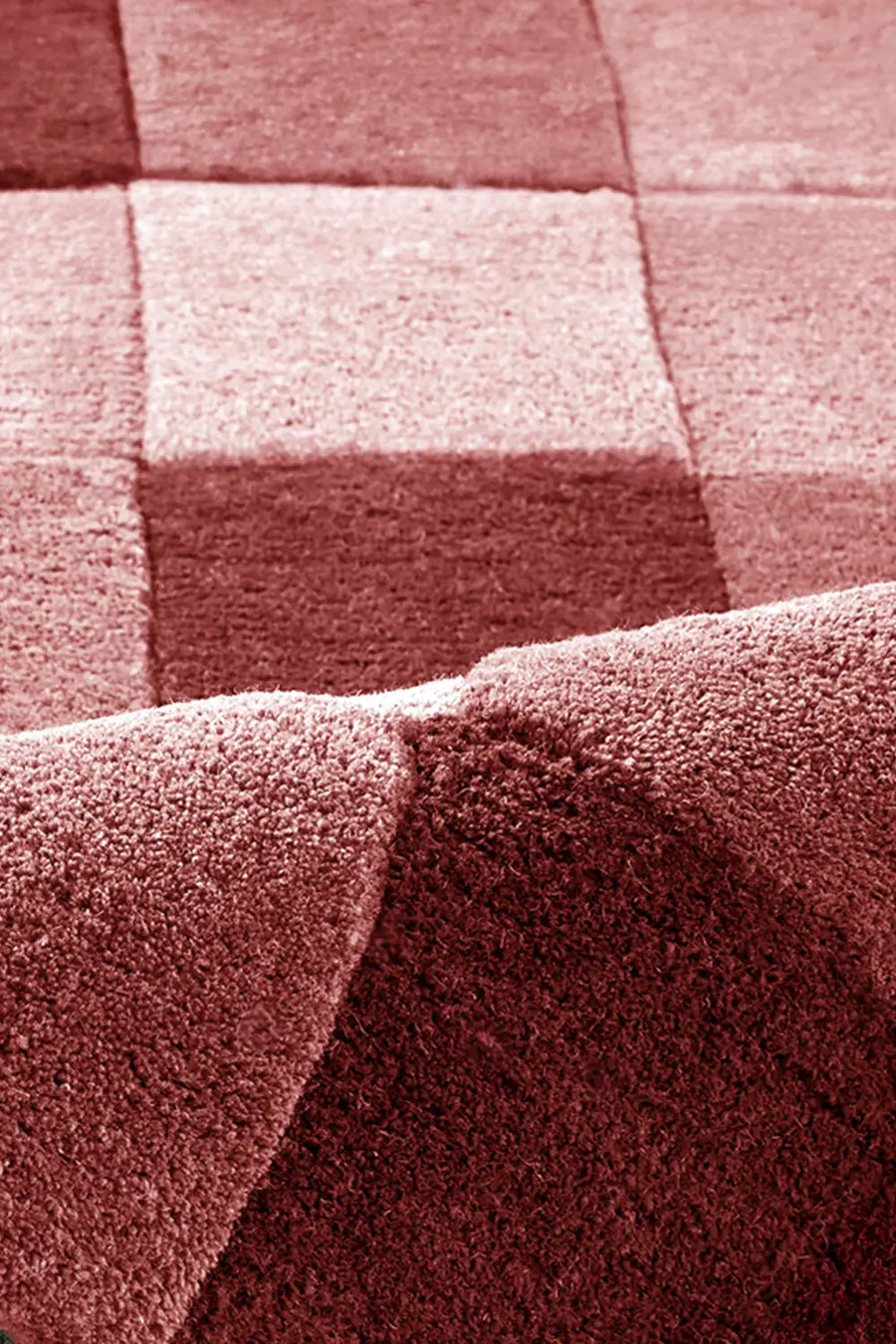 texture detail of hand tufted burgundy checkered wool rug in warm tonal palette