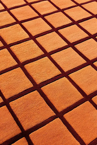 Close-up of an orange textured round rug surface with a grid pattern