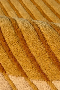 Close-up of textured yellow and tan wool rug fabric with modern graphic stripes