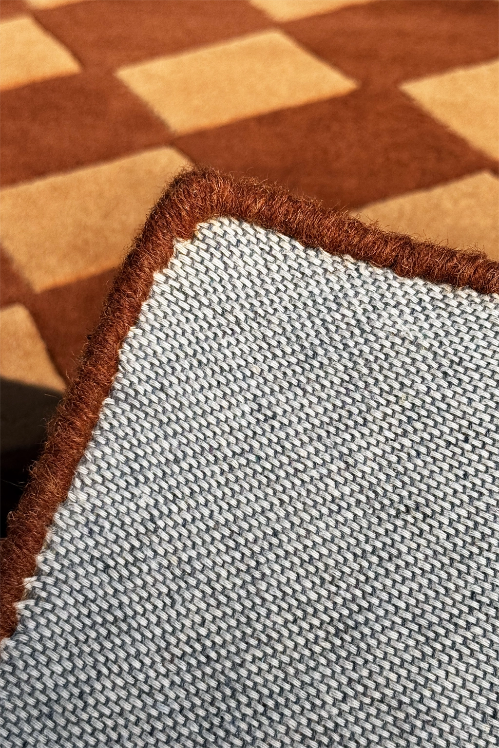 Close-up of a checkered patterned runner rug with a brown and beige design.