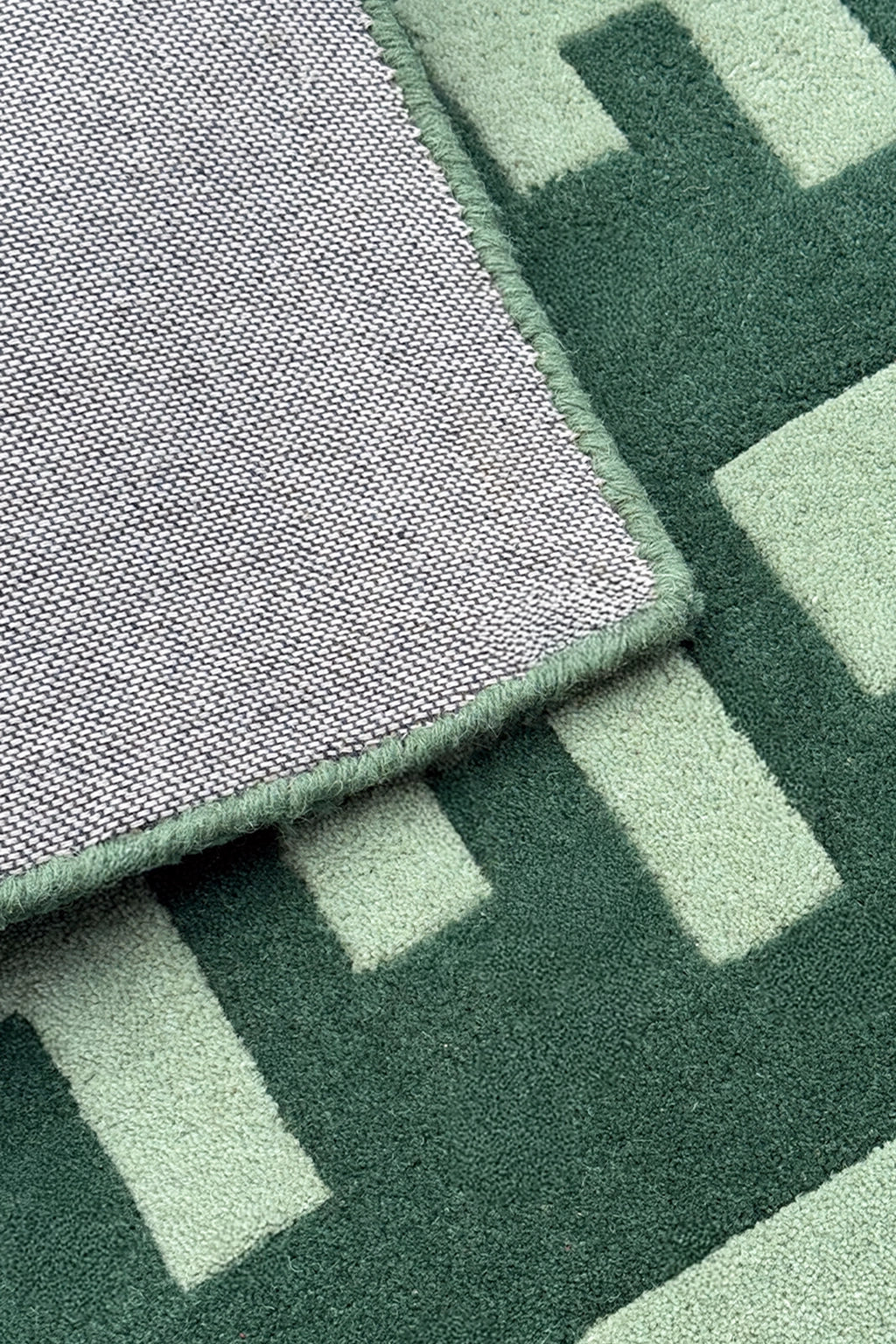 Close-up of a green wool runner rug with geometric patterns