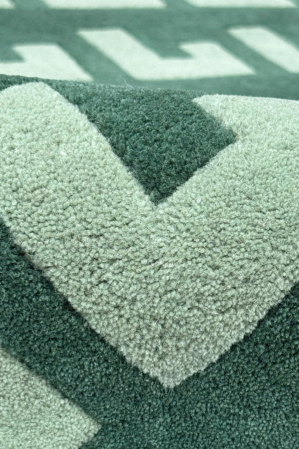 Close-up of a textured green runner rug with geometric pattern