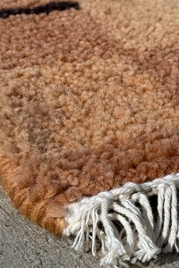 Handmade wool runner rug corner showing fringe detail and warm earthy colors in a mid-century modern pattern