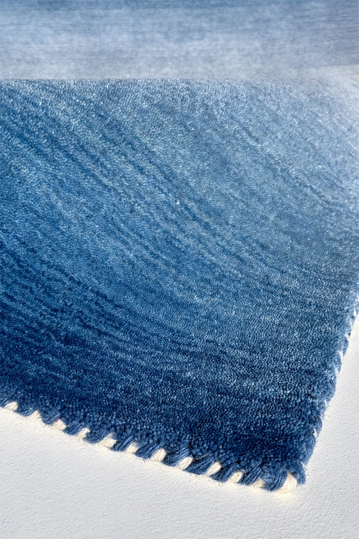 Close-up of a blue ombre rug on a light gray background