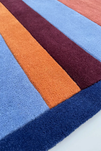 Colorful striped wool rug with blue, orange, and purple stripes on a white background