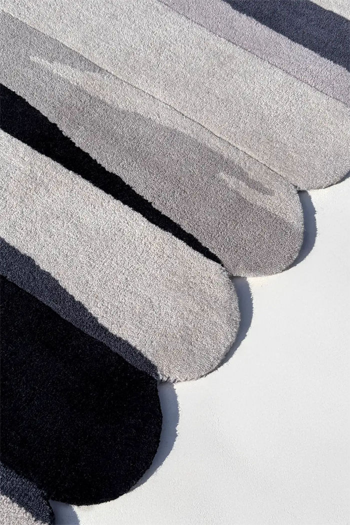 Close-up of scalloped runner rug in gray and black tufted wool with textured pile silver