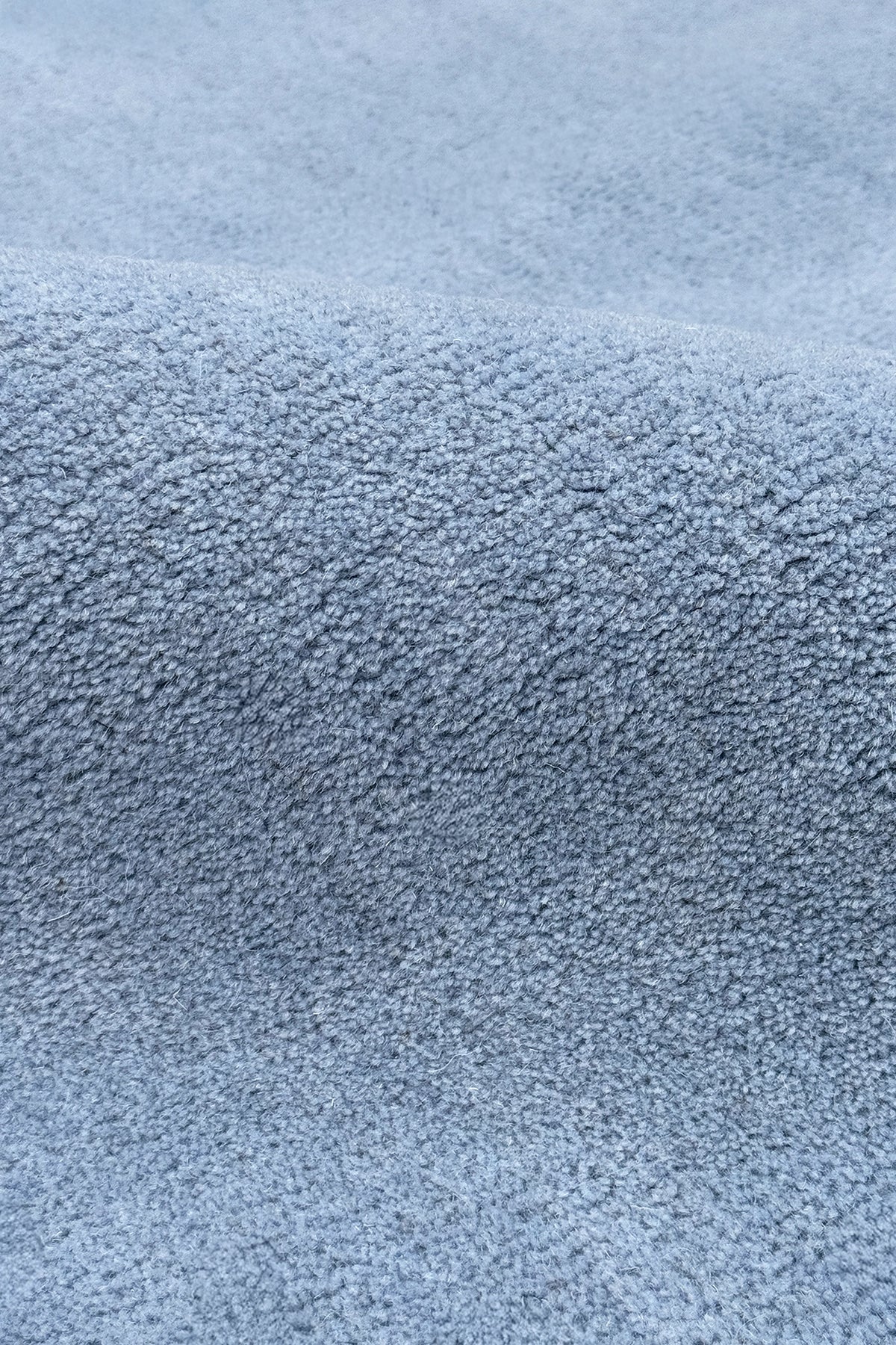 A close-up of a light blue textured rug, showing the fine woven material and soft folds.