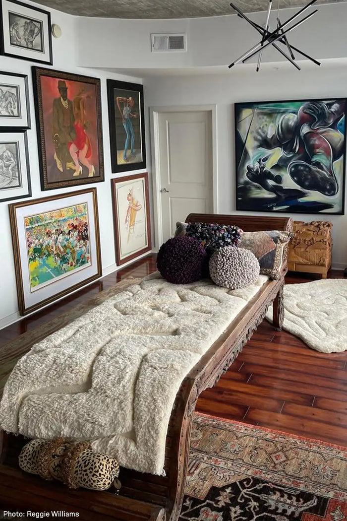 eclectic designer room with wooden bed, tan shaggy rugs colorful artwork on walls, and modern decorative pillows lifestyle