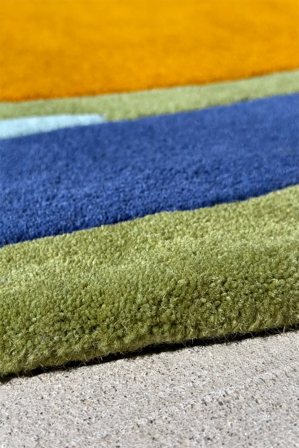 Irregular shaped wool rug with asymmetrical color blocking in ocean-inspired greens and blues