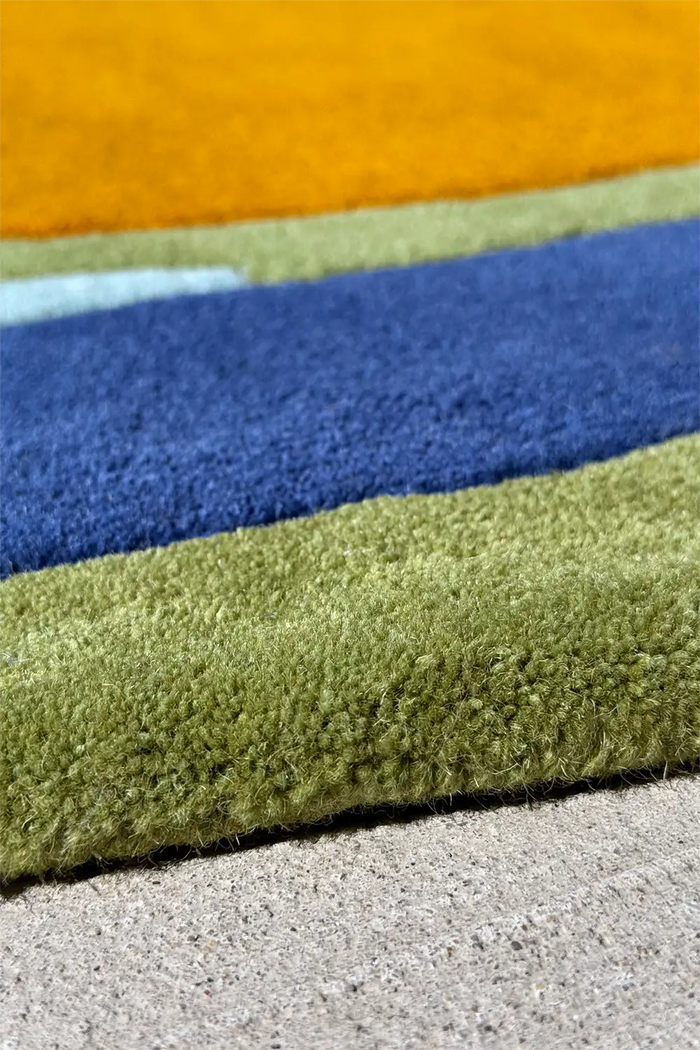 Irregular shaped wool rug with asymmetrical color blocking in ocean-inspired greens and blues