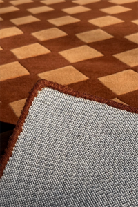 bound edge of a square brown wool rug with harlequin pattern