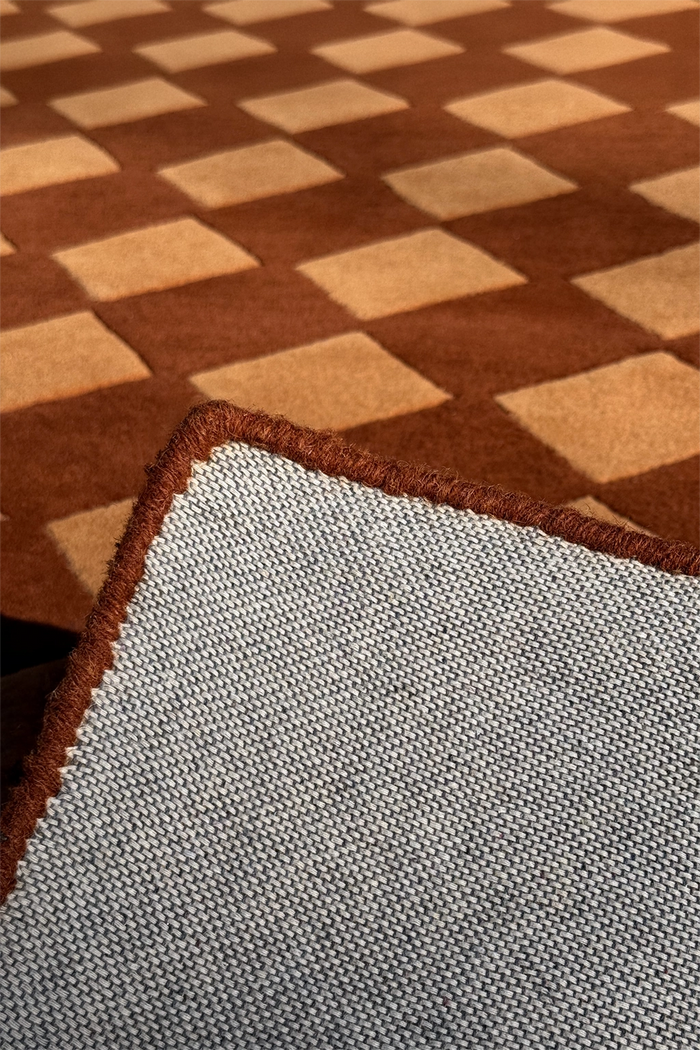 bound edge of a square brown wool rug with harlequin pattern
