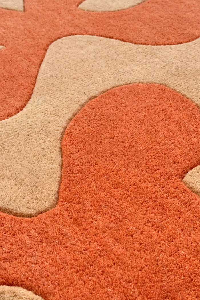 Close-up of a textured orange and beige square floral rug