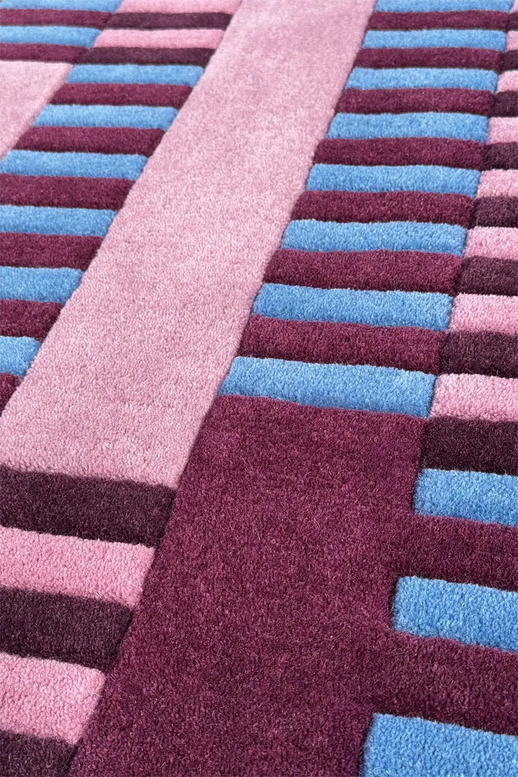 Close-up of a striped square rug with pink, blue, and purple colors.
