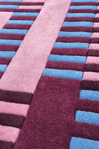 Close-up of a striped square rug with pink, blue, and purple colors.