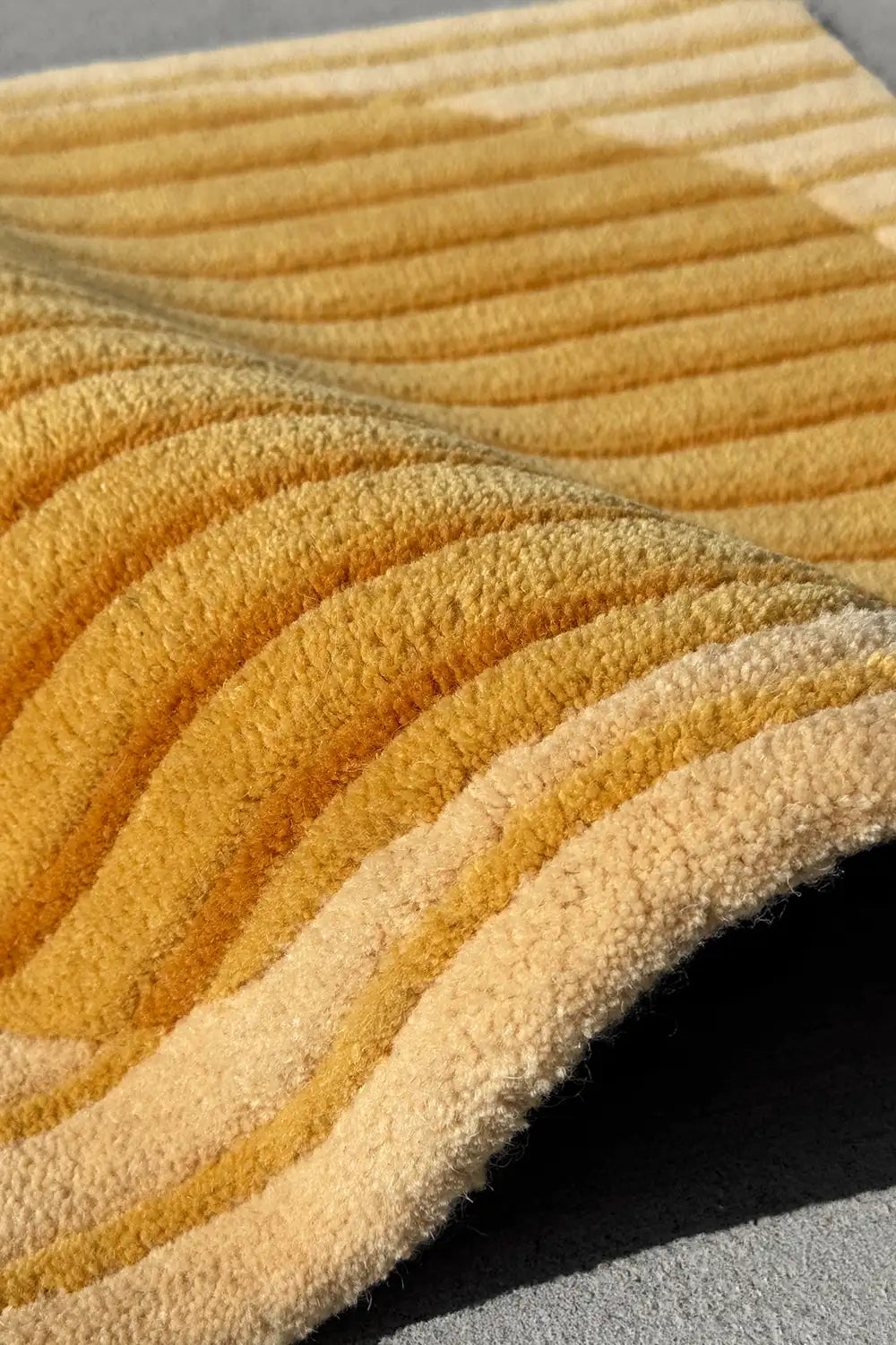 Textured yellow square rug with geometric gold pattern on a neutral surface