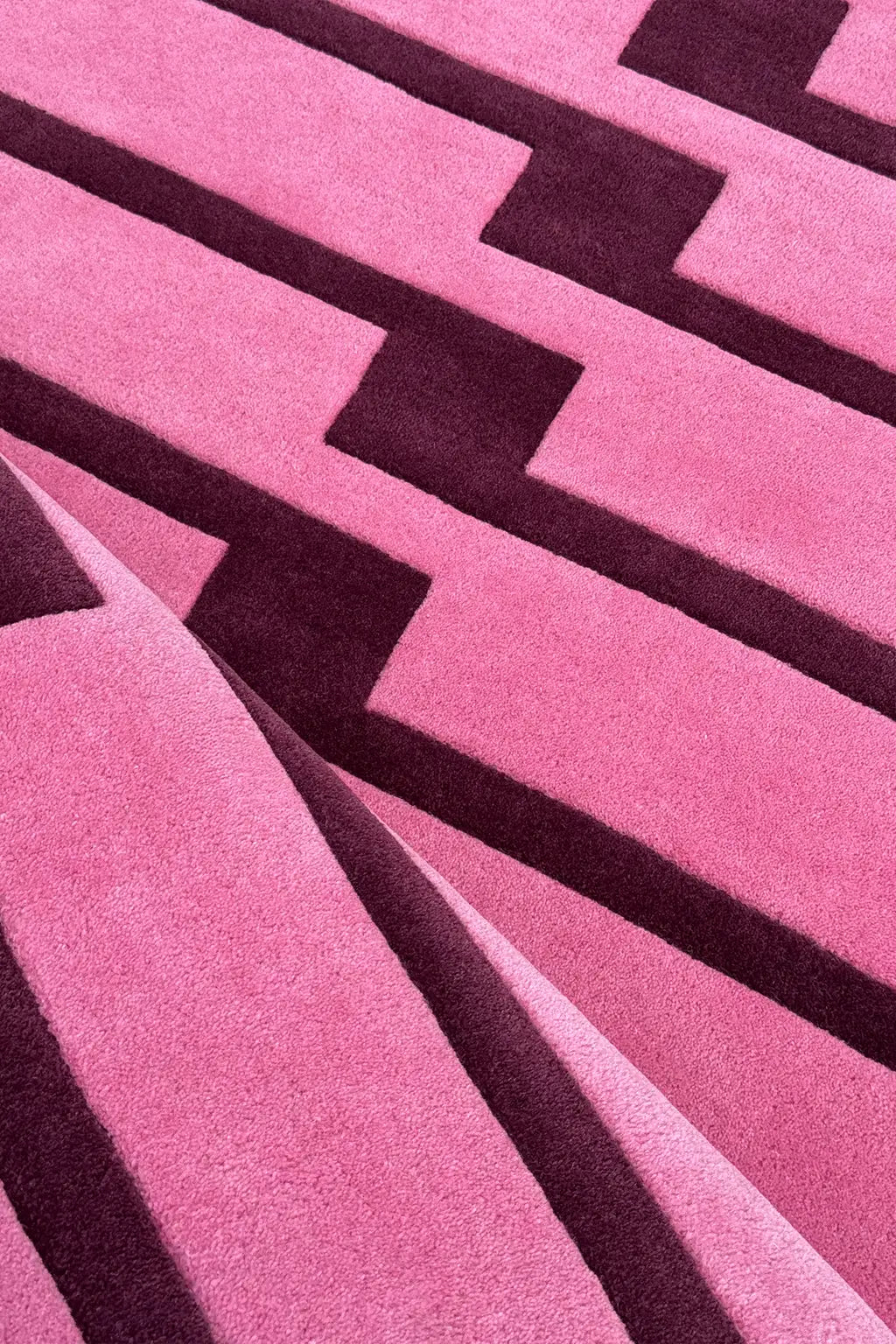 Close-up of a pink and purple geometric striped patterned area rug