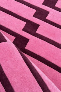 Close-up of a pink and purple geometric striped patterned area rug