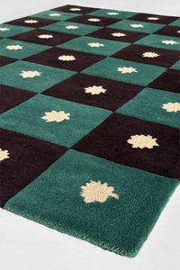 Checkered rug in black and green wool with star leaf patterns on a white background