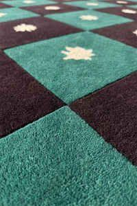 Close-up of a checkered pattern rug with alternating black and teal green squares texture