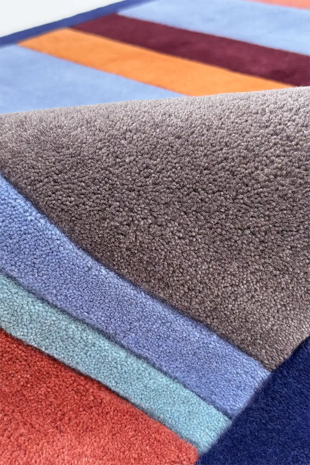 Multicolored striped rug with various colors including blue, orange, and gray.