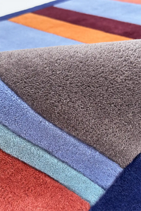 Multicolored striped rug with various colors including blue, orange, and gray.