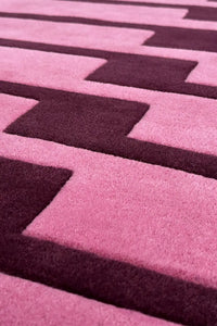 Close-up of a pink and purple geometric patterned square rug texture