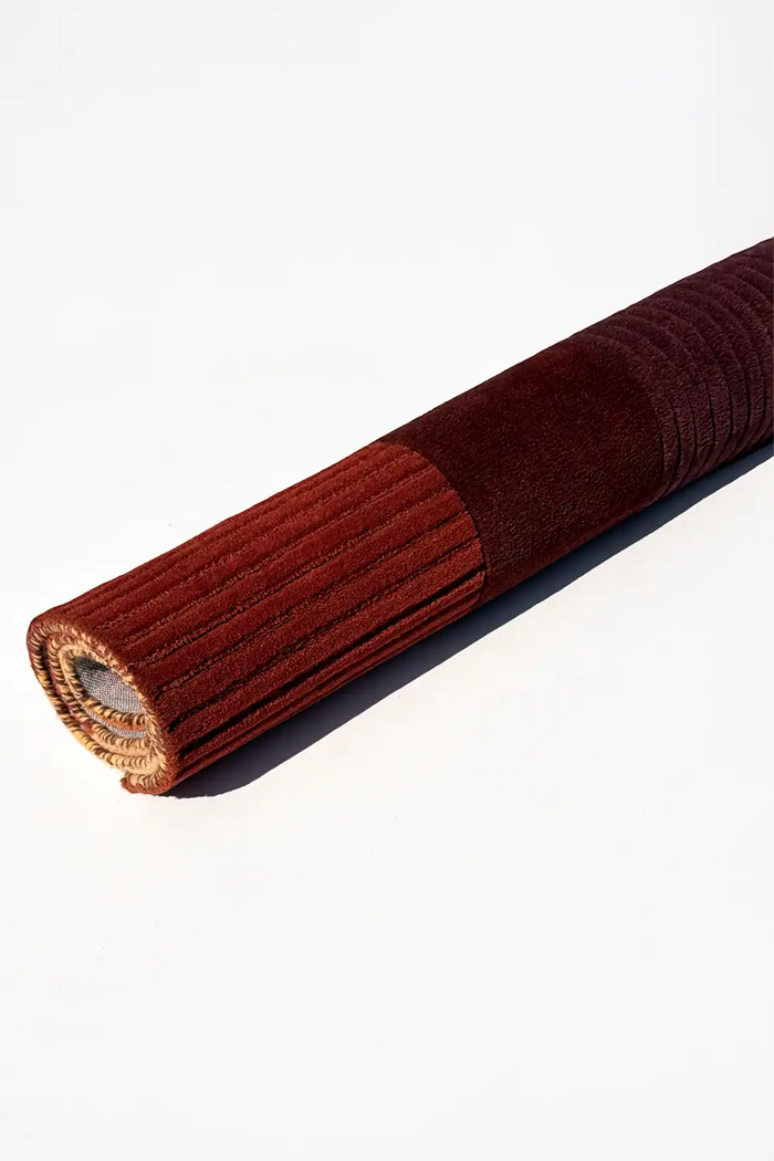 brown textured rug rolled on a white background