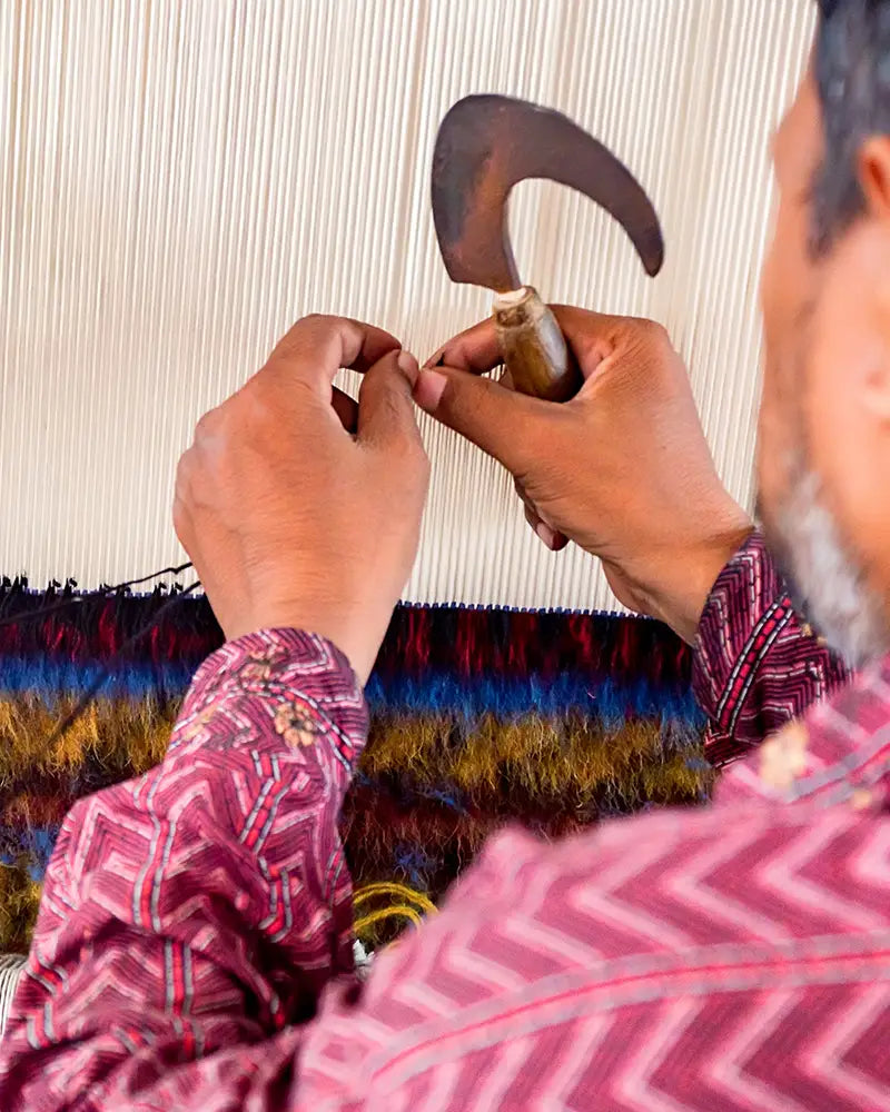 Person weaving with a traditional loom, focusing on the hands and tools.