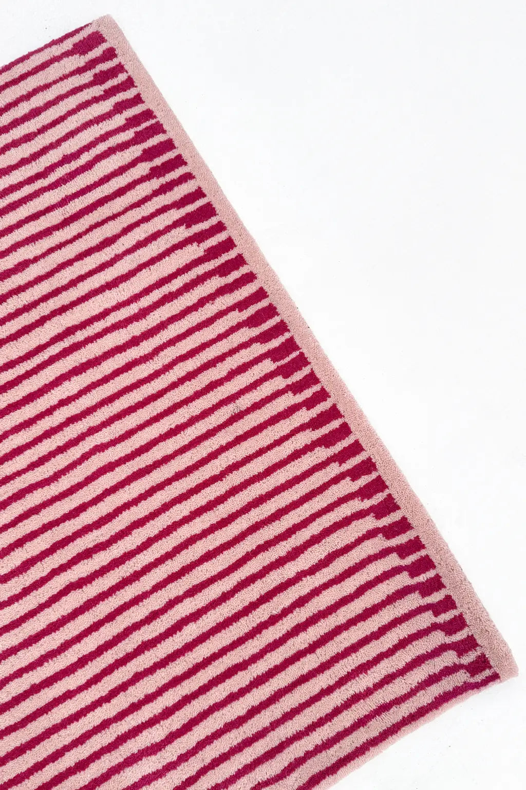 Striped hot pink and tan rug on a white background