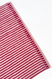 Striped hot pink and tan rug on a white background