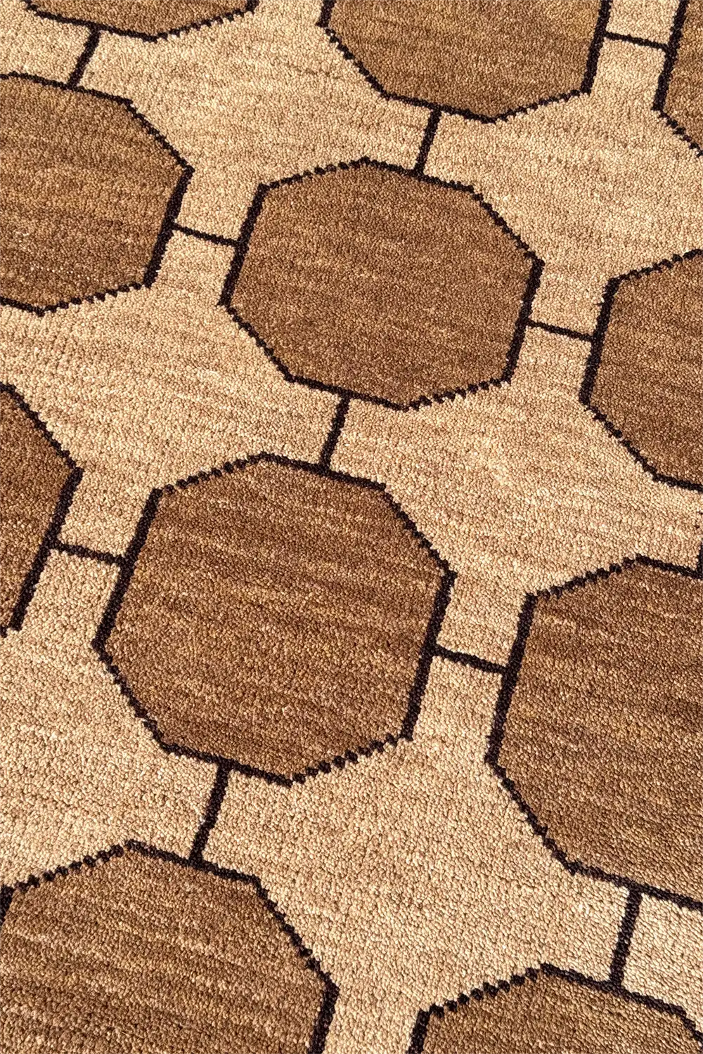 Close-up of a octagonal wool patterned rug with neutral brown and beige colors.