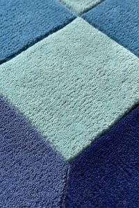 Close-up of a textured blue and green rug with geometric pattern