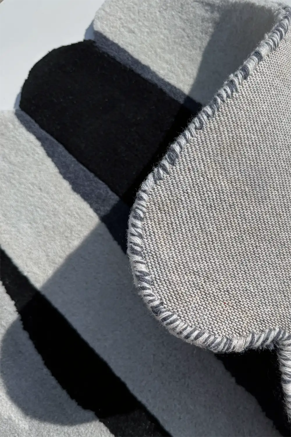 Close-up of a textured gray and black scalloped wool rug surface silver