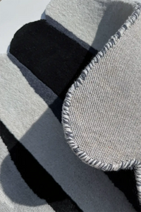 Close-up of a textured gray and black scalloped wool rug surface silver