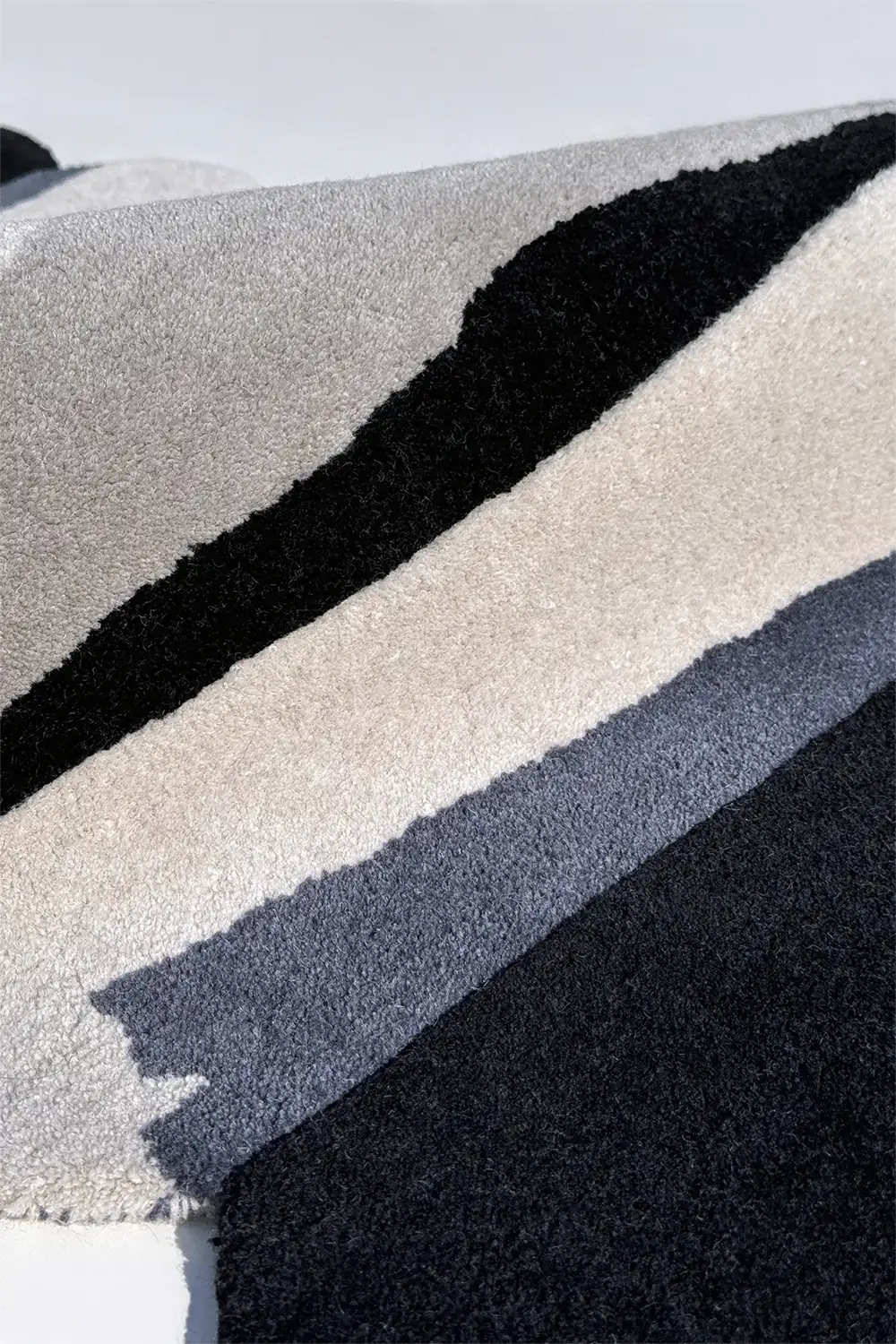 Close-up of textured runner rug with black, gray, and white stripes.