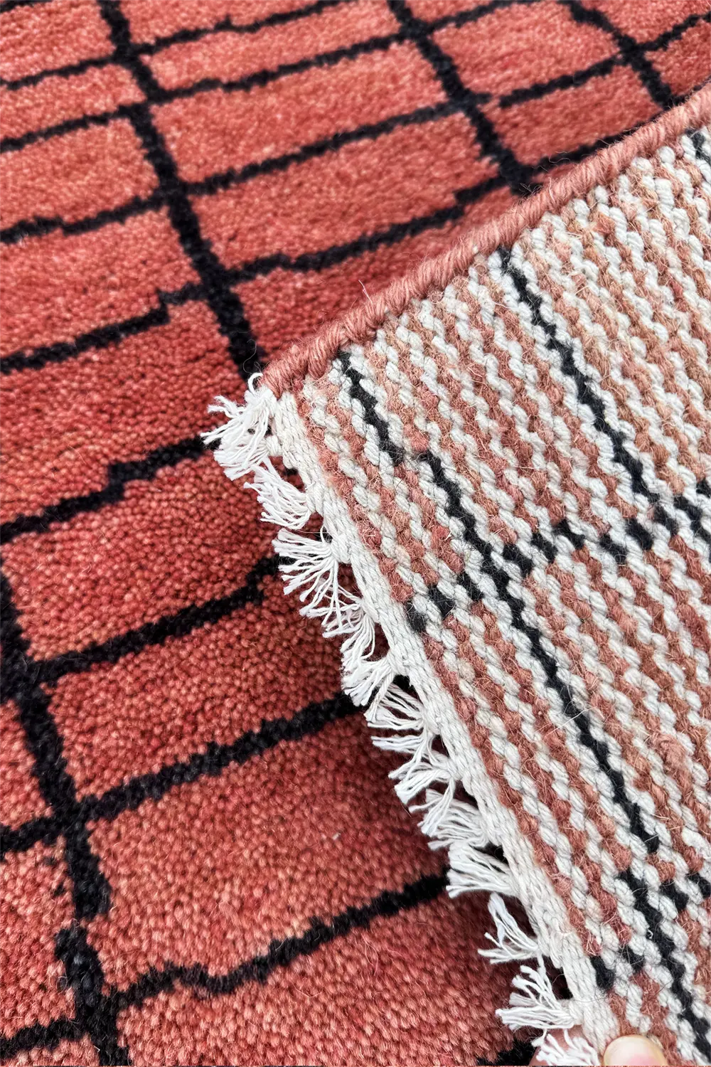Close-up of a textured rusty red rug with a checkered pattern