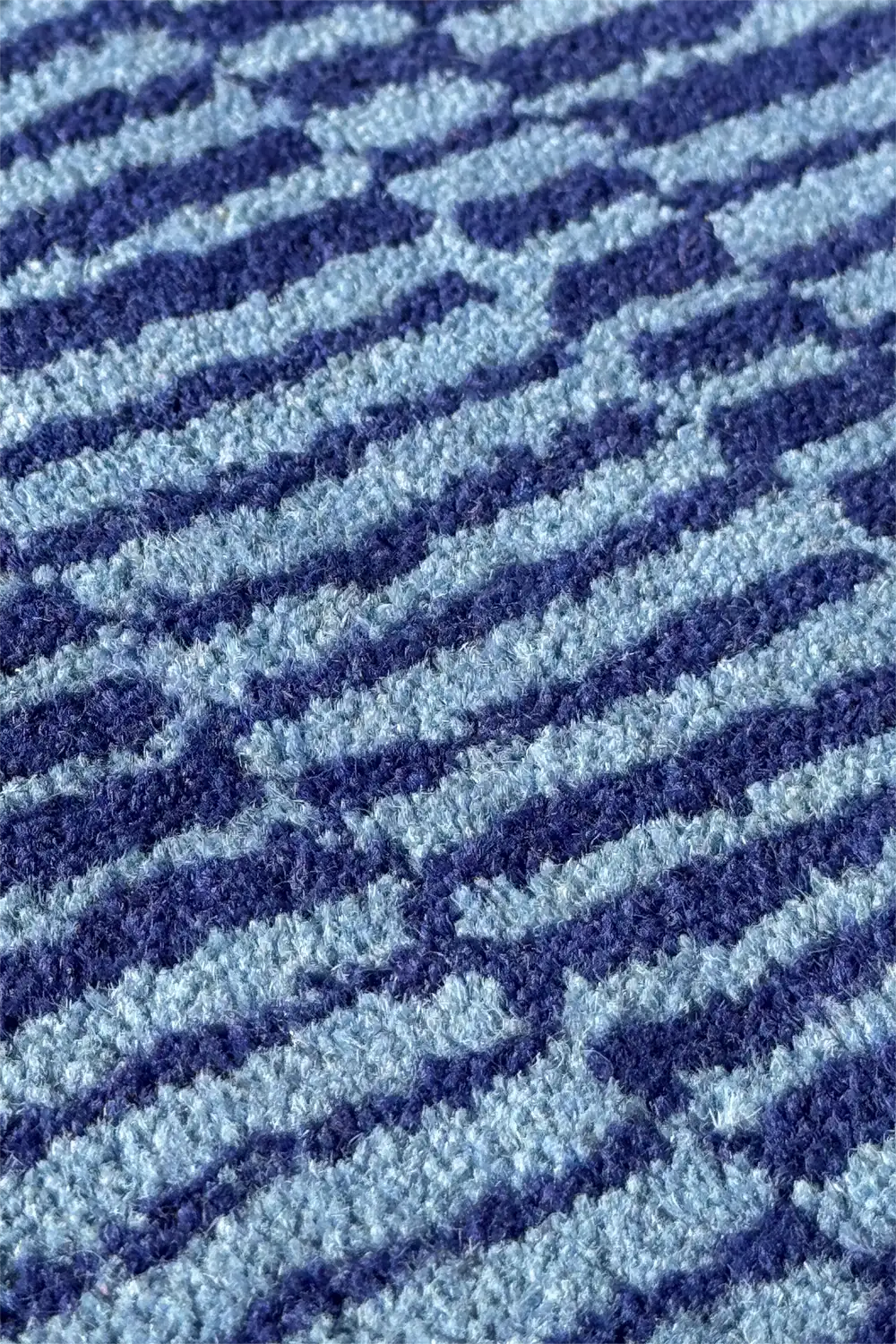 Detailed view of blue plaid style rug with graphic woven pattern in dark and light blue stripes