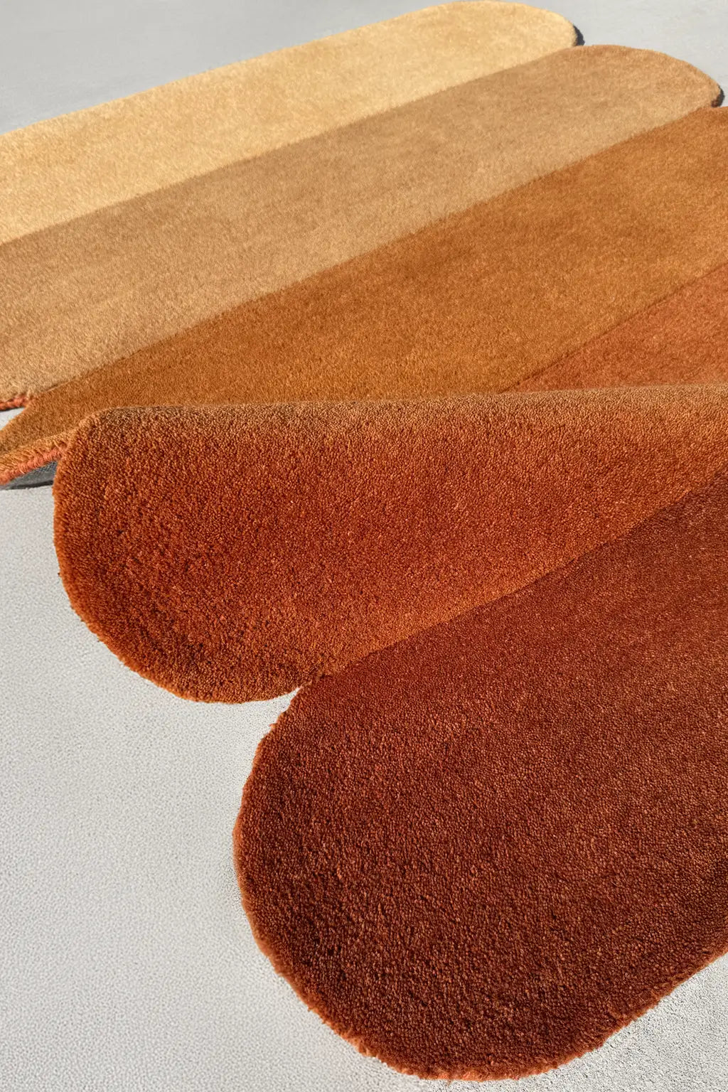 Burnt orange and tan rug with layered curved silhouette, perfect for warm, neutral living rooms