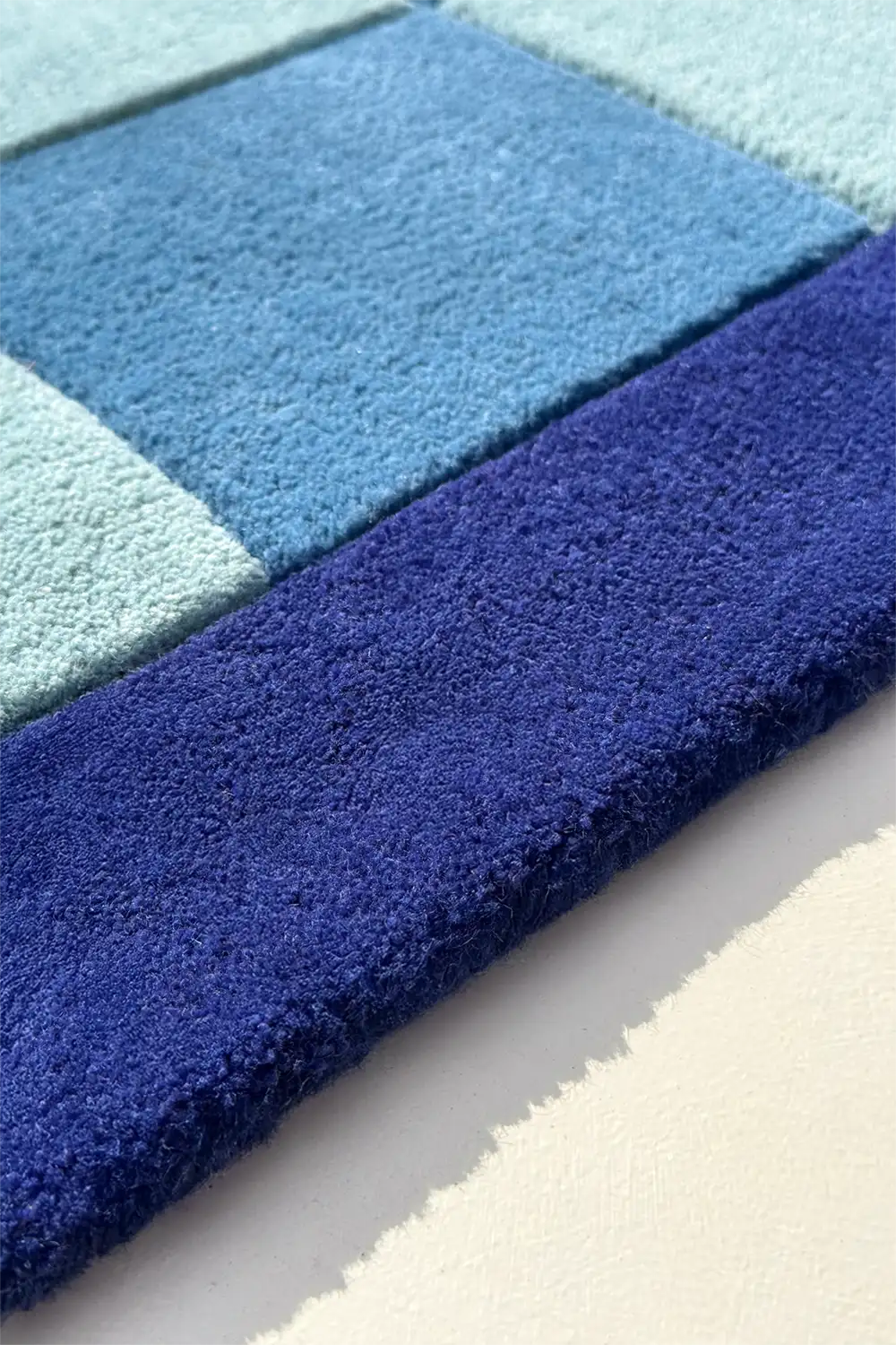 Blue and green checkered rug on a light gray surface