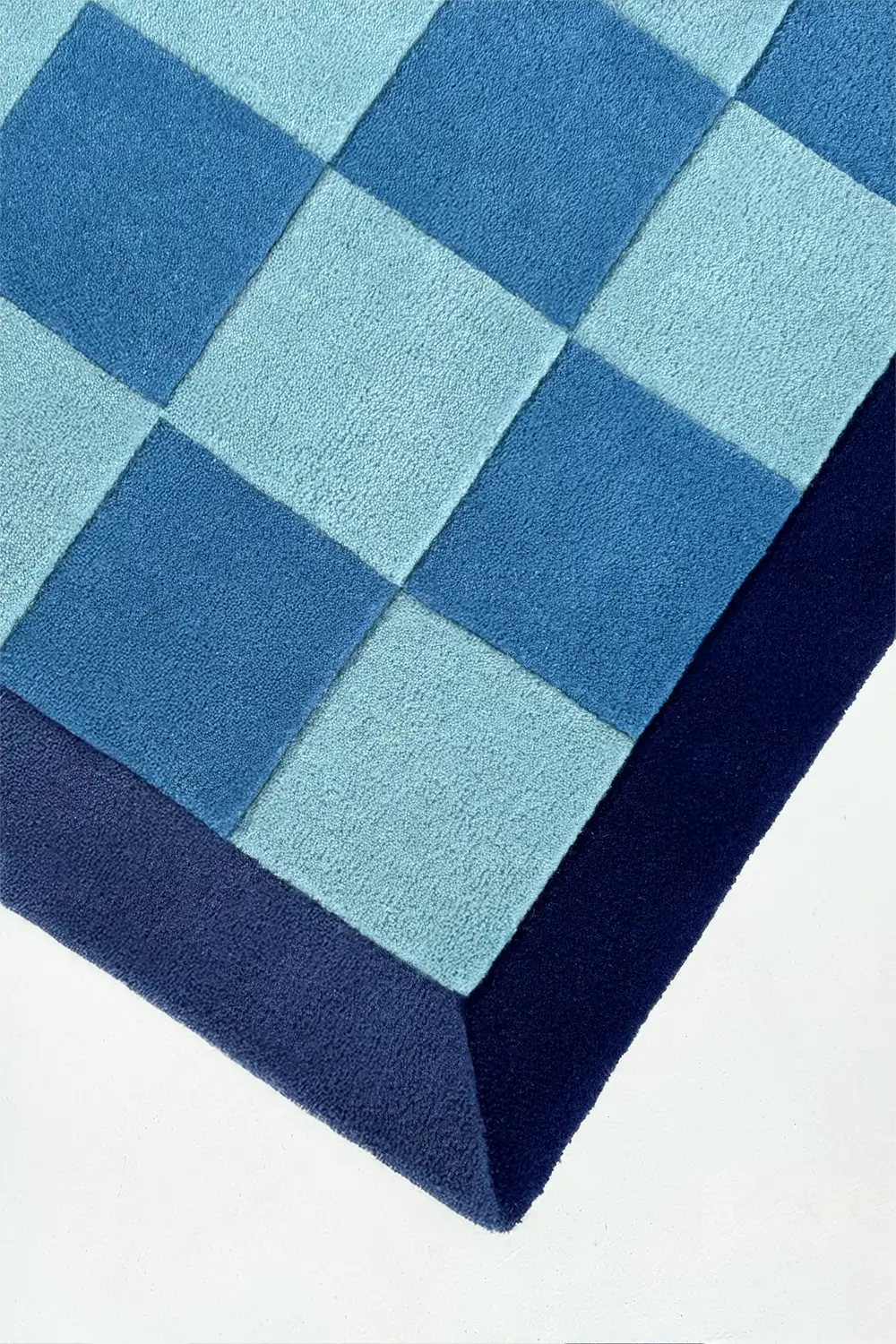 square blue checkered rug with a geometric pattern on a white background